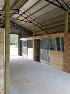 The inside of a horse barn with wooden stalls.
