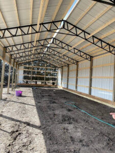 The inside of a horse barn with a metal roof.