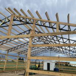 A barn being built with wooden beams and trusses.
